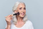 senior woman applying make up brush