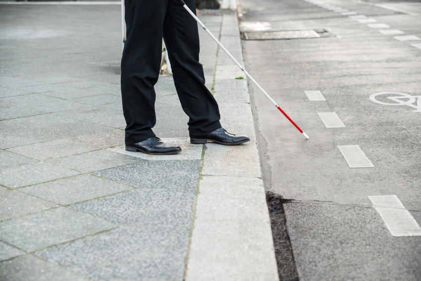 man walking with white cane curb